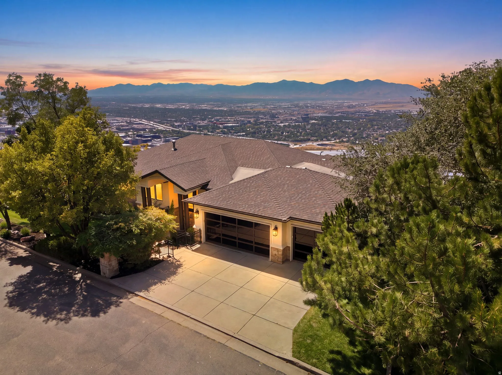 Sloped lot featuring a multi-level residence with a multi-car garage, concrete driveway, and established landscaping