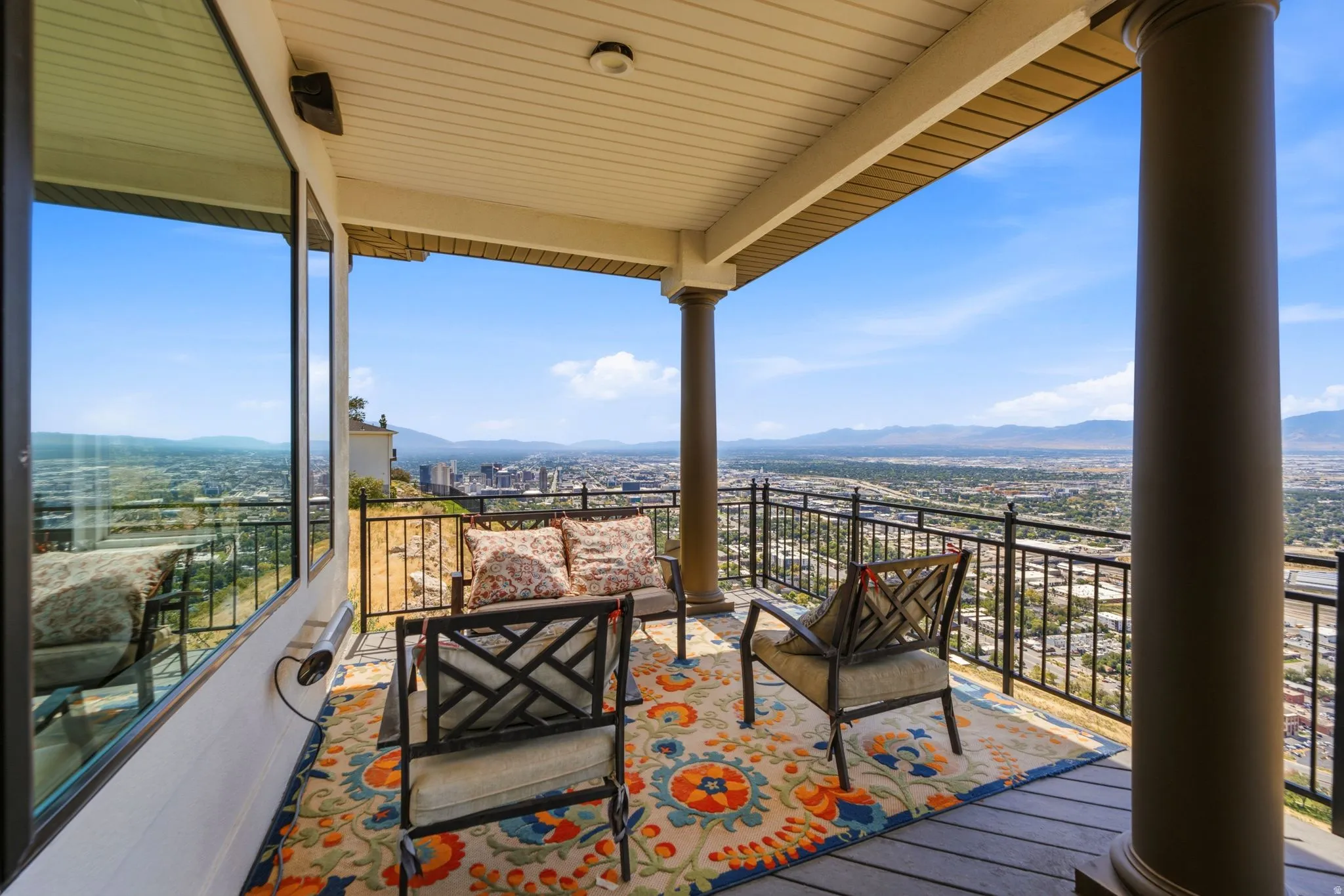 Expansive covered balcony featuring a durable deck surface, robust support pillars, and decorative wrought iron railing