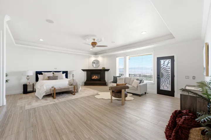 Spacious room featuring wood-finish flooring, a tray ceiling, and a built-in fireplace with a dark wood mantel