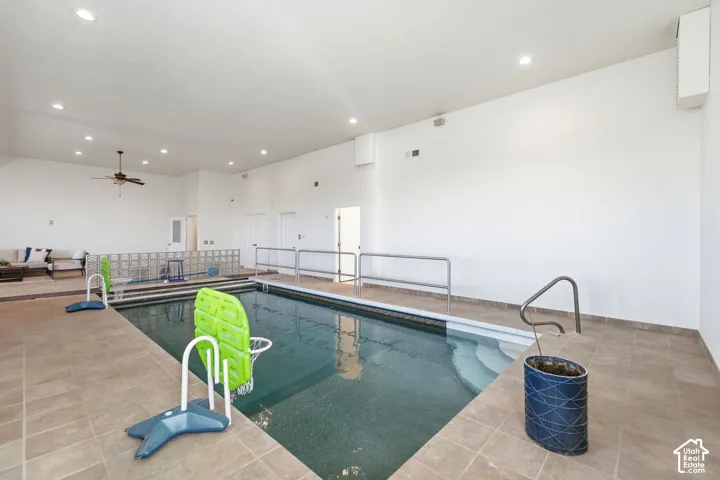 Indoor swimming pool featuring a tiled surround, integrated steps, and handrails