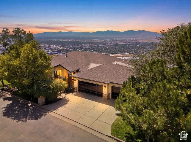 Sloped lot featuring a multi-level residence with a multi-car garage, concrete driveway, and established landscaping