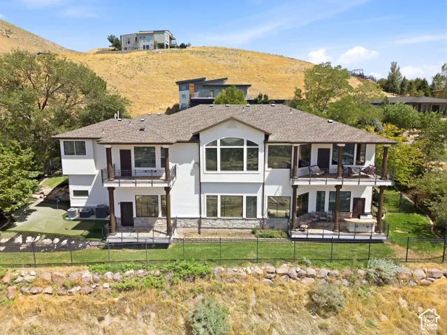 Multi-level exterior with multiple balconies, a lower-level patio, and a putting green