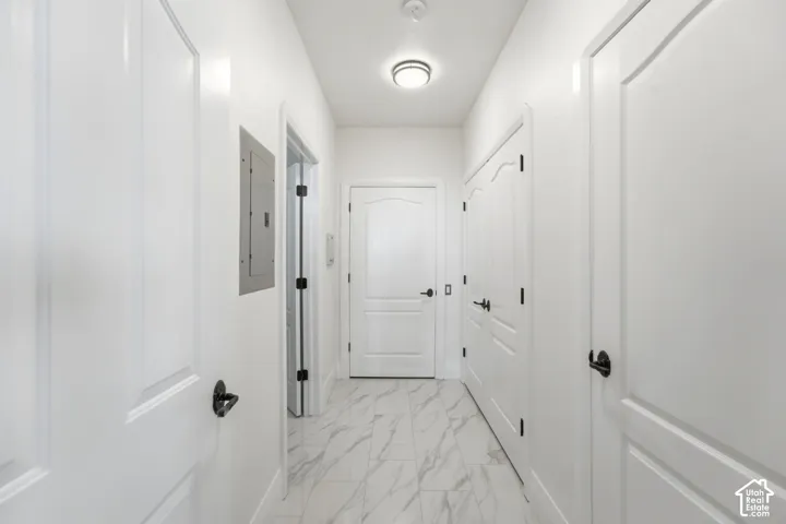Hallway featuring white panel doors, matte black hardware, recessed lighting, and marble-look tile flooring