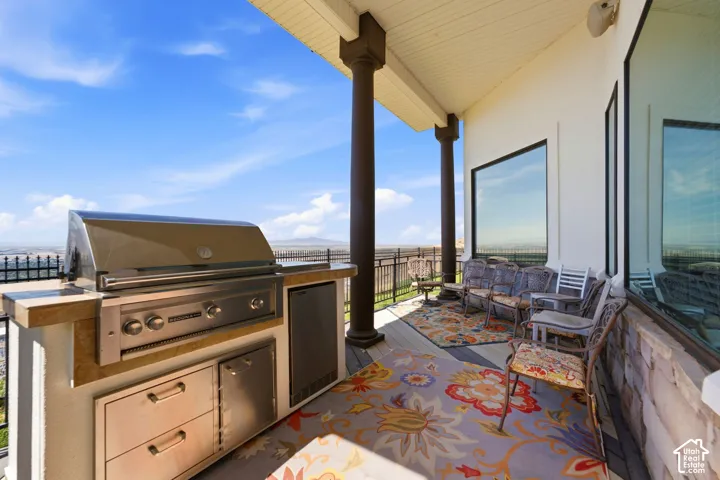 Covered outdoor patio featuring a built-in grill station, integrated stainless steel appliances, and large windows