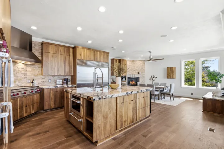 Open-concept kitchen featuring wood-finish cabinetry, a large kitchen island with integrated microwave, stainless steel appliances, and wood-finish flooring