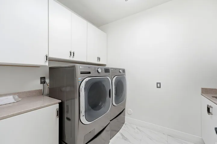 White cabinetry with brushed nickel hardware, light-toned countertop, and integrated sink
