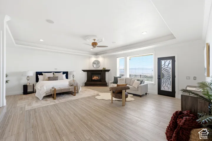 Spacious room featuring wood-finish flooring, a tray ceiling, and a built-in fireplace with a dark wood mantel