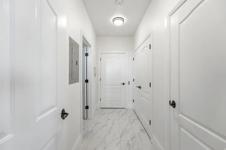 Hallway featuring white panel doors, matte black hardware, recessed lighting, and marble-look tile flooring