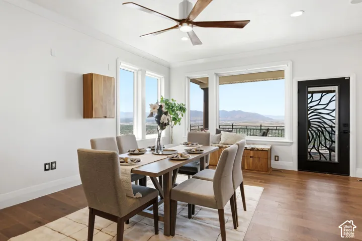 Hardwood flooring, white crown molding, large picture windows, wood-finish wall cabinet, and a decorative glass-paneled door
