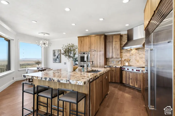 Spacious kitchen featuring an expansive island with a polished countertop, wood-finish cabinetry, stainless steel appliances, and a stone-tiled backsplash