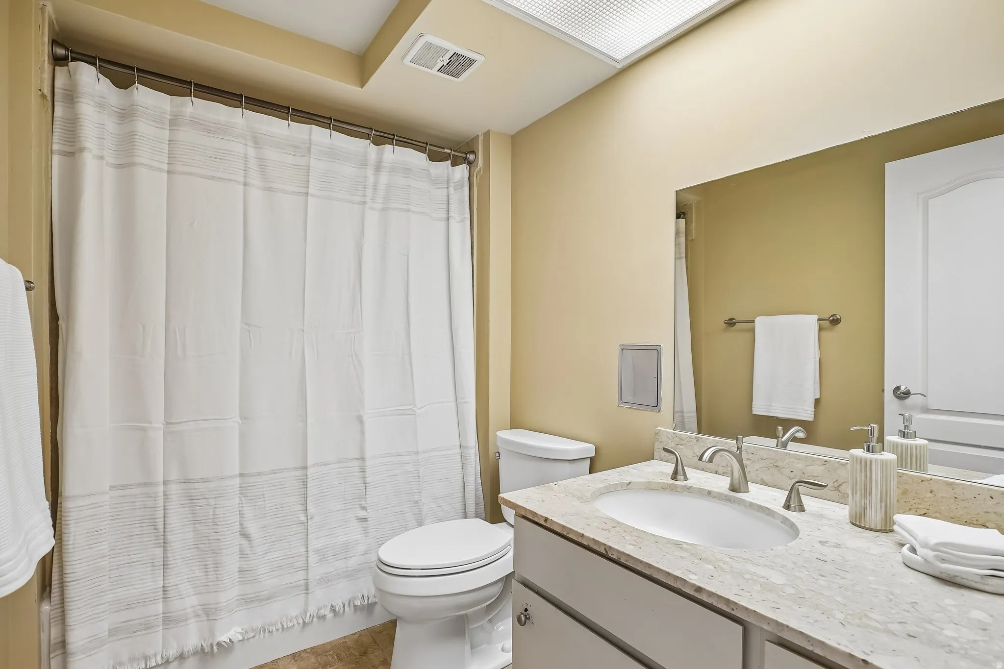 Vanity with a light-toned stone countertop, integrated sink, and brushed nickel fixtures