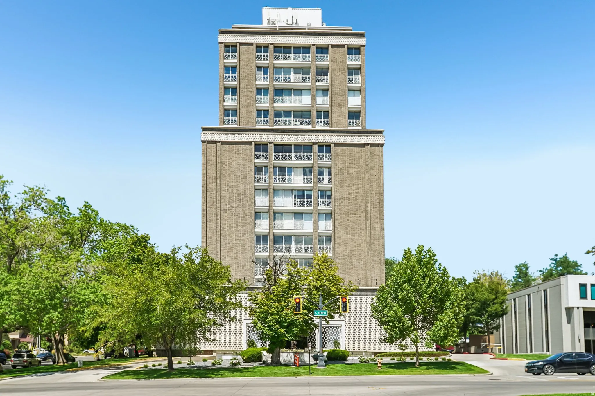 High-rise building with brick facade and multiple balconies, featuring decorative band courses and a street-level entrance