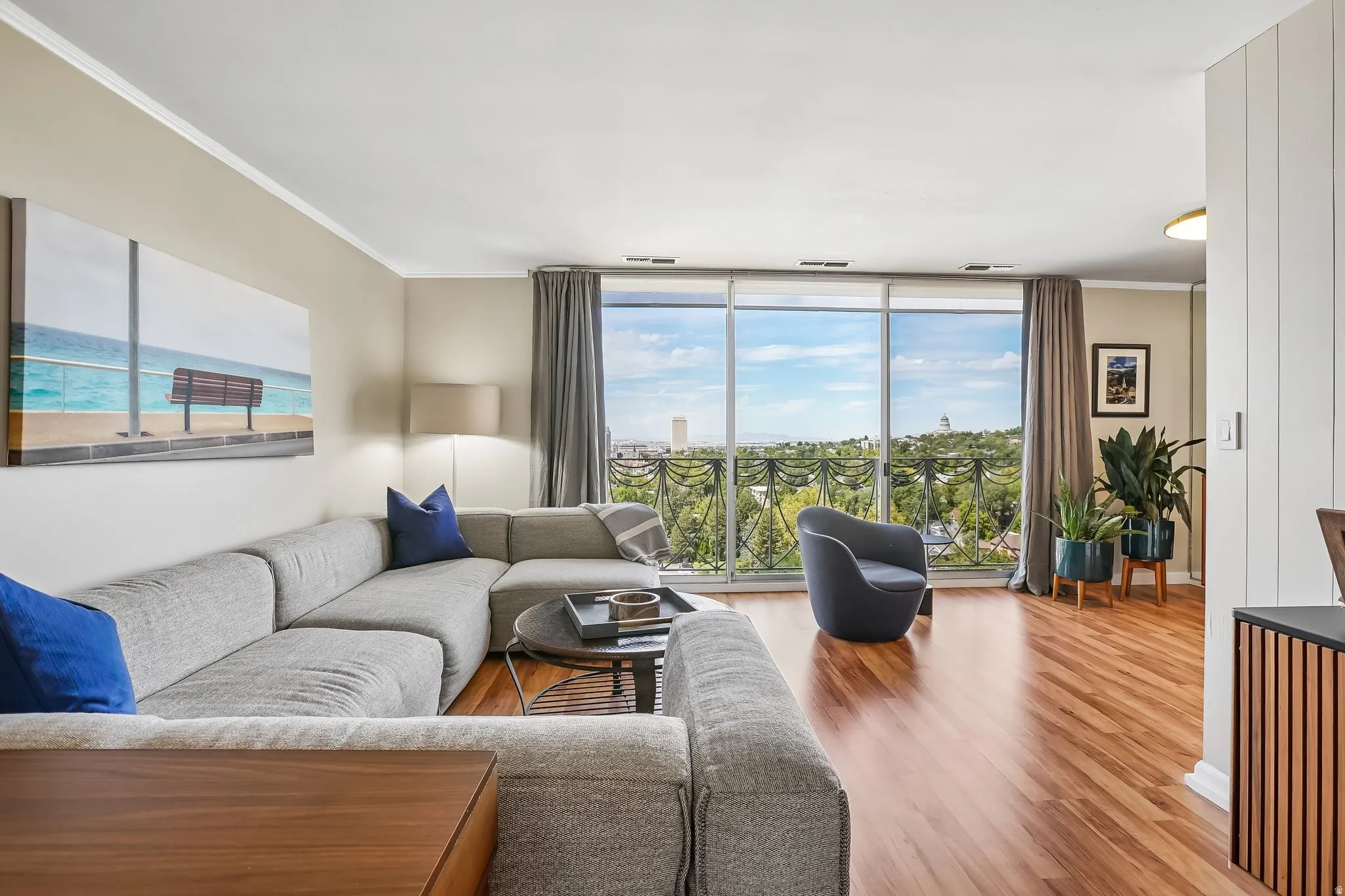 Expansive windows with city and landscape scenery, hardwood flooring, crown molding, and light-toned wall finishes