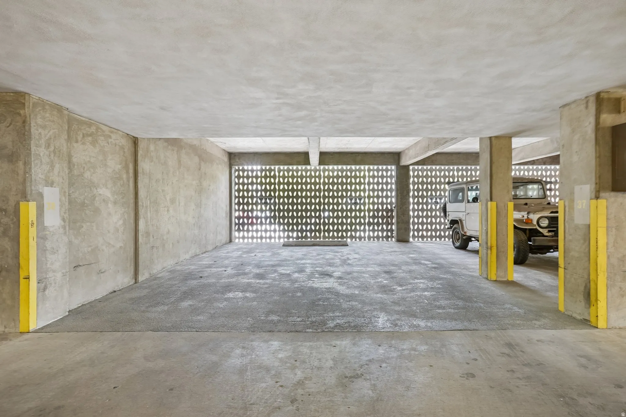 Concrete flooring with textured ceiling, concrete support columns, and perforated block wall