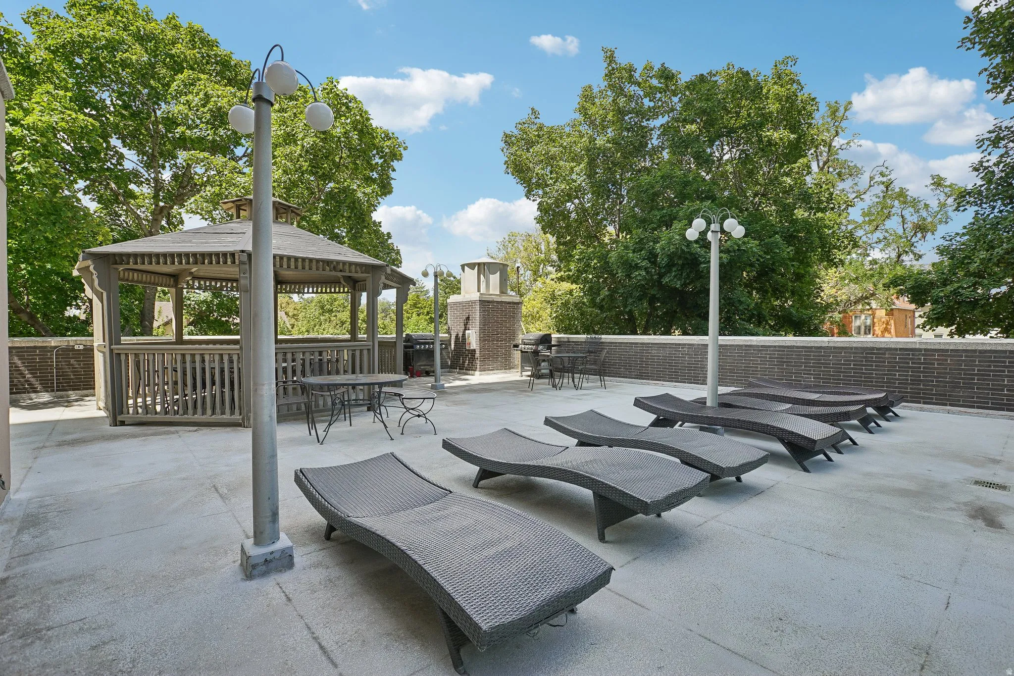 Rooftop deck featuring a wooden gazebo, brick perimeter wall, and built-in streetlights