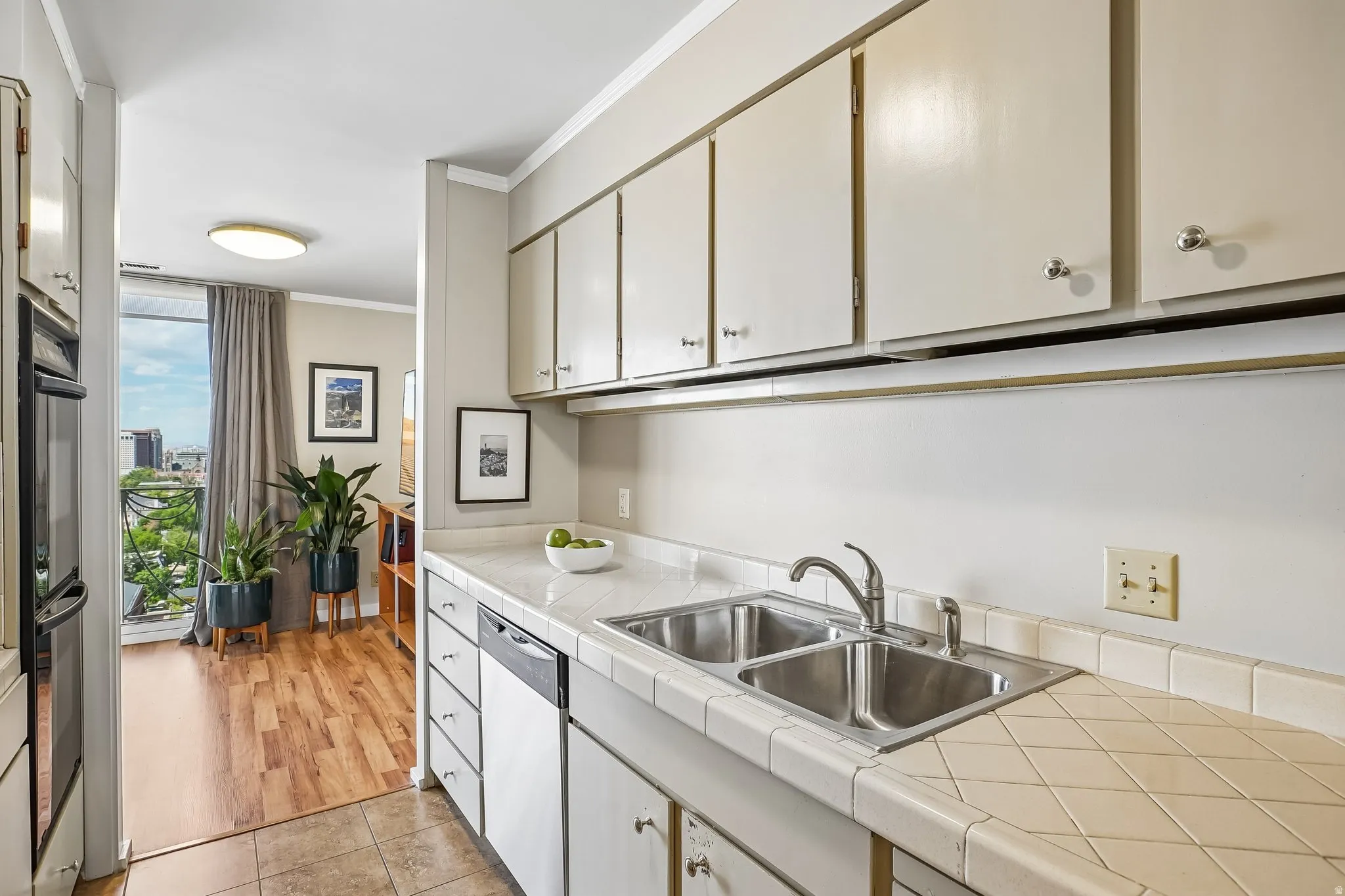 Full-height upper cabinetry, durable tile countertops, dual basin stainless steel sink, and wood-finish flooring