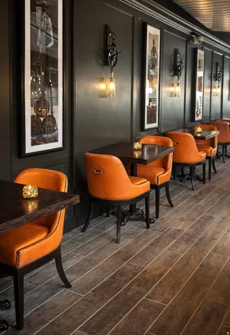 Wood-finish flooring, dark paneled walls, and wall-mounted sconce lighting