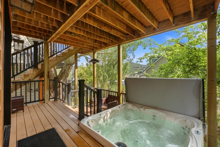 Expansive outdoor deck featuring a hot tub, wood-finish decking, and black metal railings