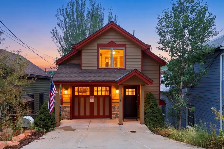 Two-story exterior with warm-toned siding, a deep red trim, and a shingle roof