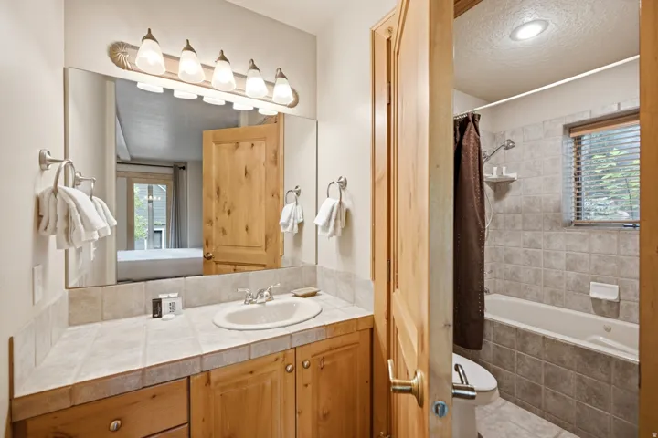 Vanity with a tiled countertop, single sink, and wood-finish cabinetry
