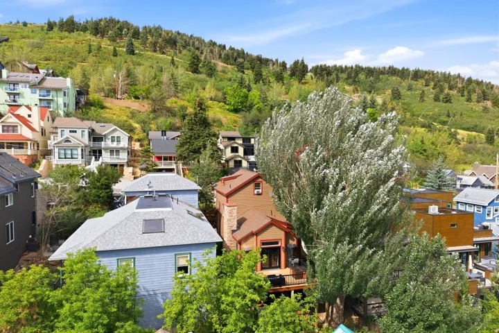 Multiple residential structures with varied architectural styles, nestled on a verdant hillside with extensive tree cover