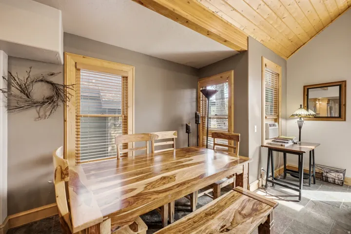Vaulted wood-paneled ceiling, wood-trimmed windows with blinds, gray wall paint, and slate-style flooring