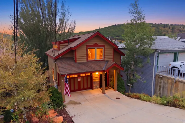 Two-story residence featuring a covered entry, attached garage with panel door, and dormer windows