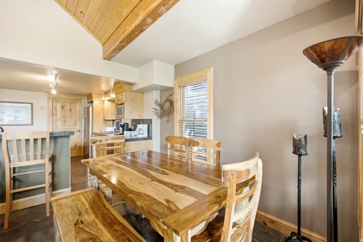 Wood-planked ceiling with exposed beams, wood-finish flooring, kitchen with light wood cabinetry, and granite countertops