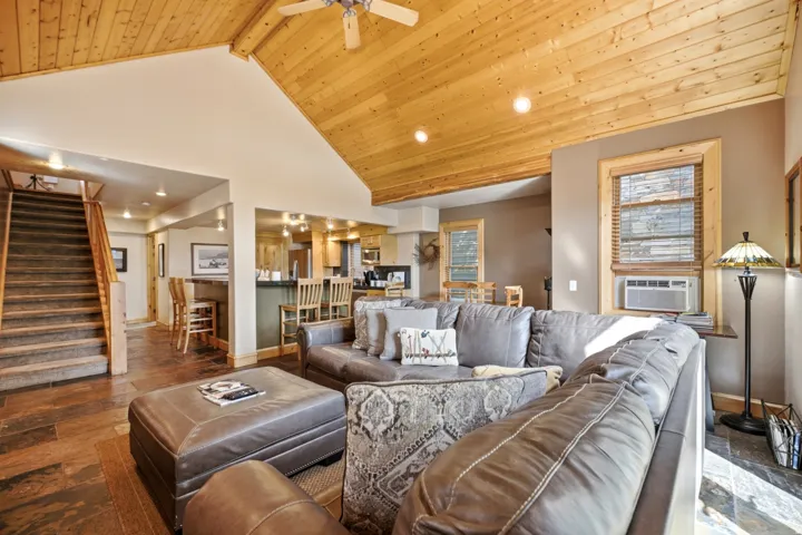 Vaulted wood-paneled ceiling with recessed lighting, stone-look tile flooring, and a built-in breakfast bar with seating