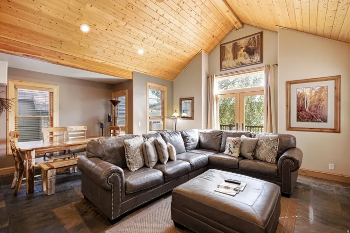 Vaulted wood-paneled ceilings with recessed lighting, French doors, large windows, and dark tile flooring