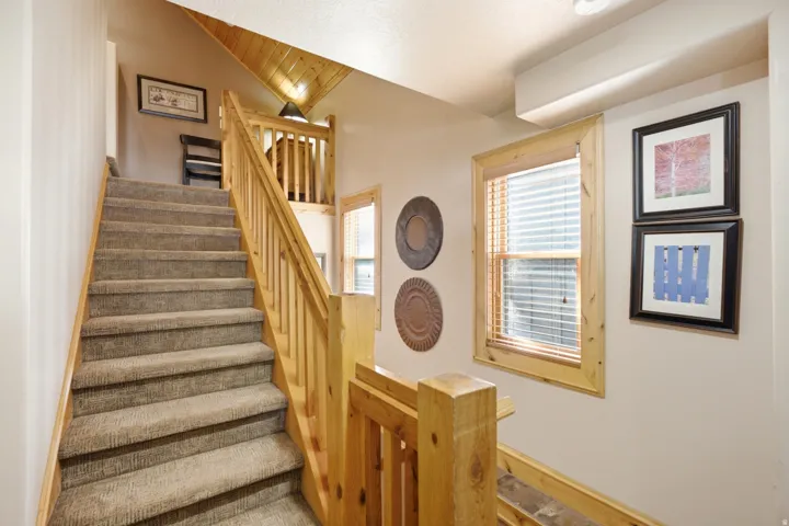Carpeted staircase with natural wood handrails and balusters