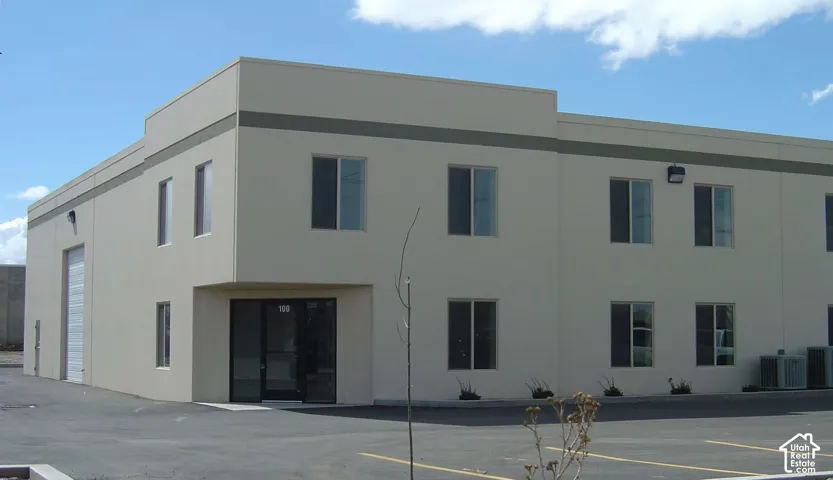 Two-story commercial building featuring multiple windows, a large roll-up door, and a prominent entry