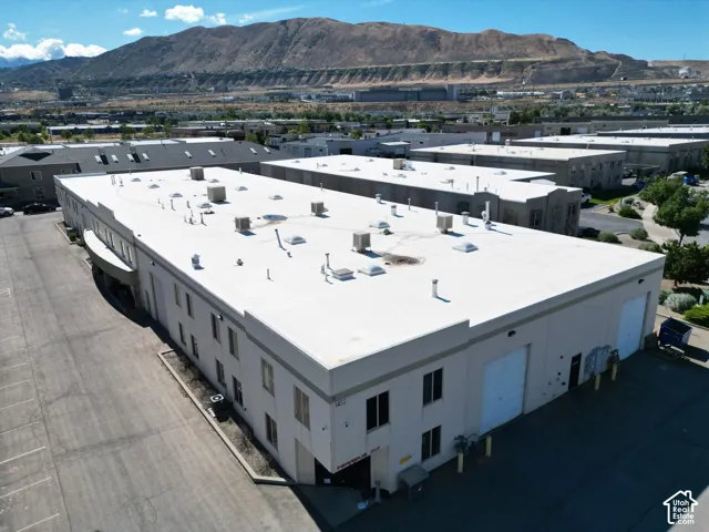 Large commercial building featuring a flat roof, multiple skylights, and multiple roll-up garage doors
