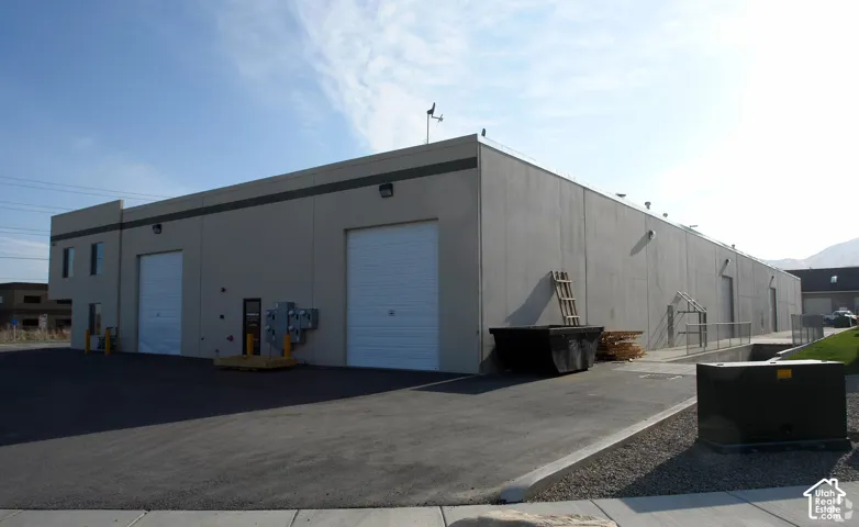 Industrial building with multiple bay doors, paved lot, exterior lighting, and sloped access points