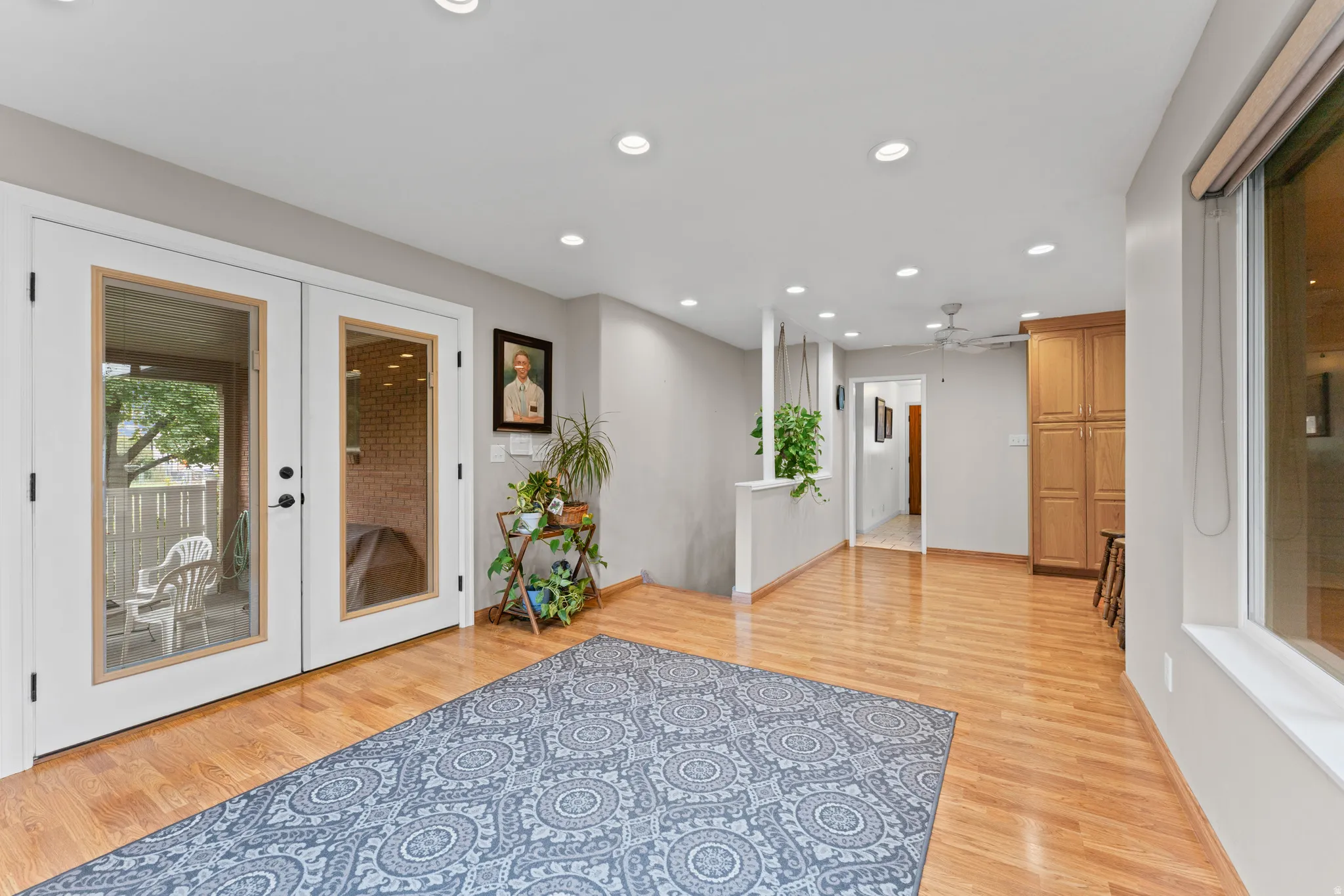 Wood-finish flooring throughout, recessed ceiling lighting, built-in wooden cabinetry, and white double doors with glass panels