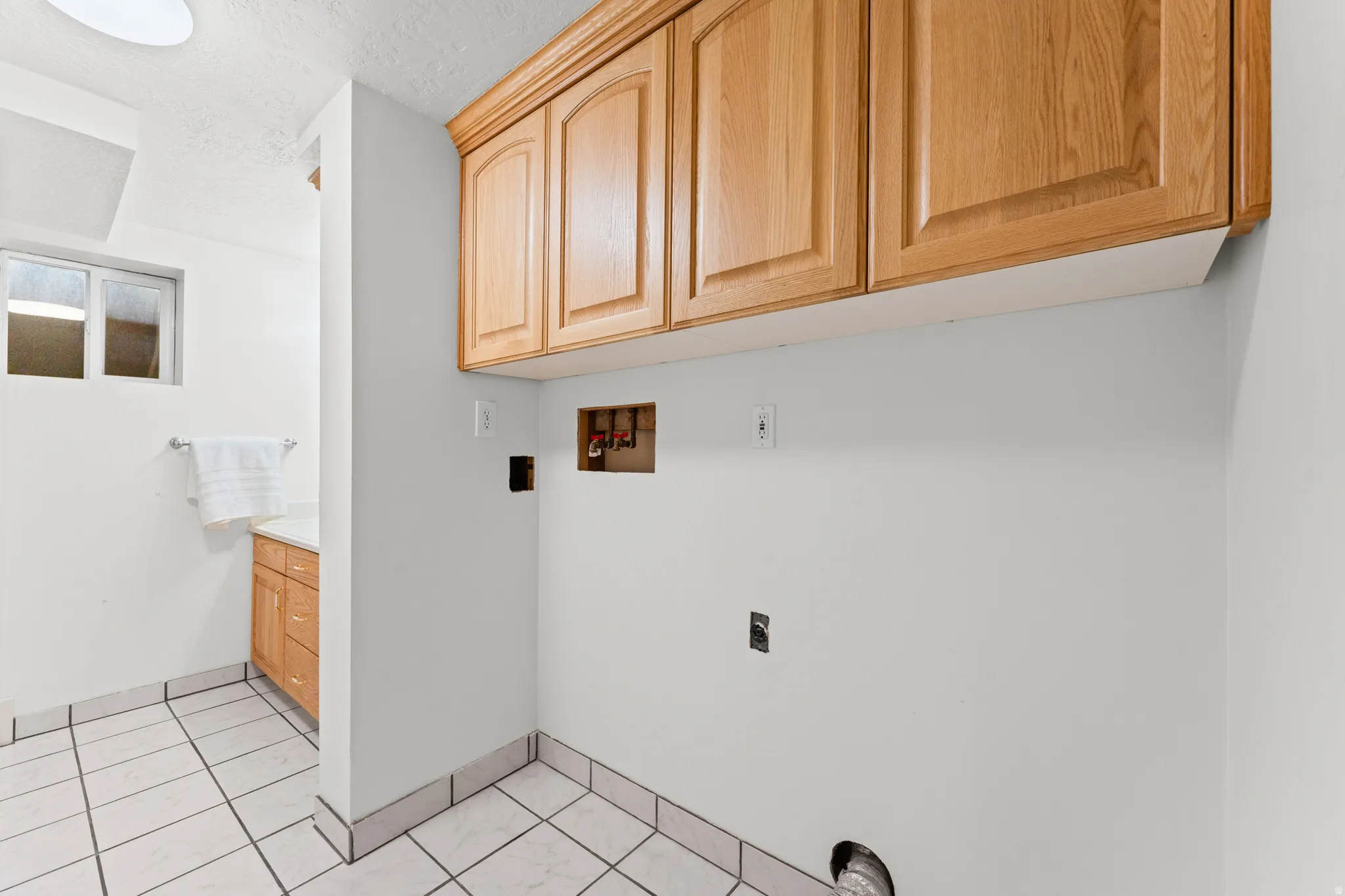 Laundry area featuring overhead wood cabinetry and tile flooring