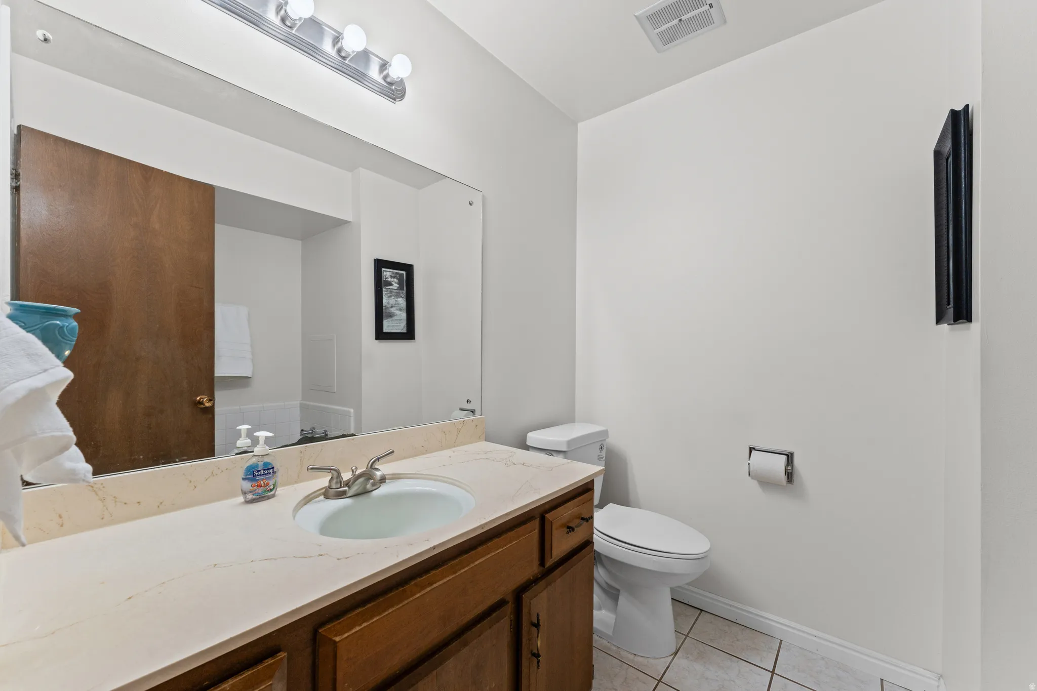 Vanity with a light-colored countertop, integrated sink, and wood-finish cabinetry