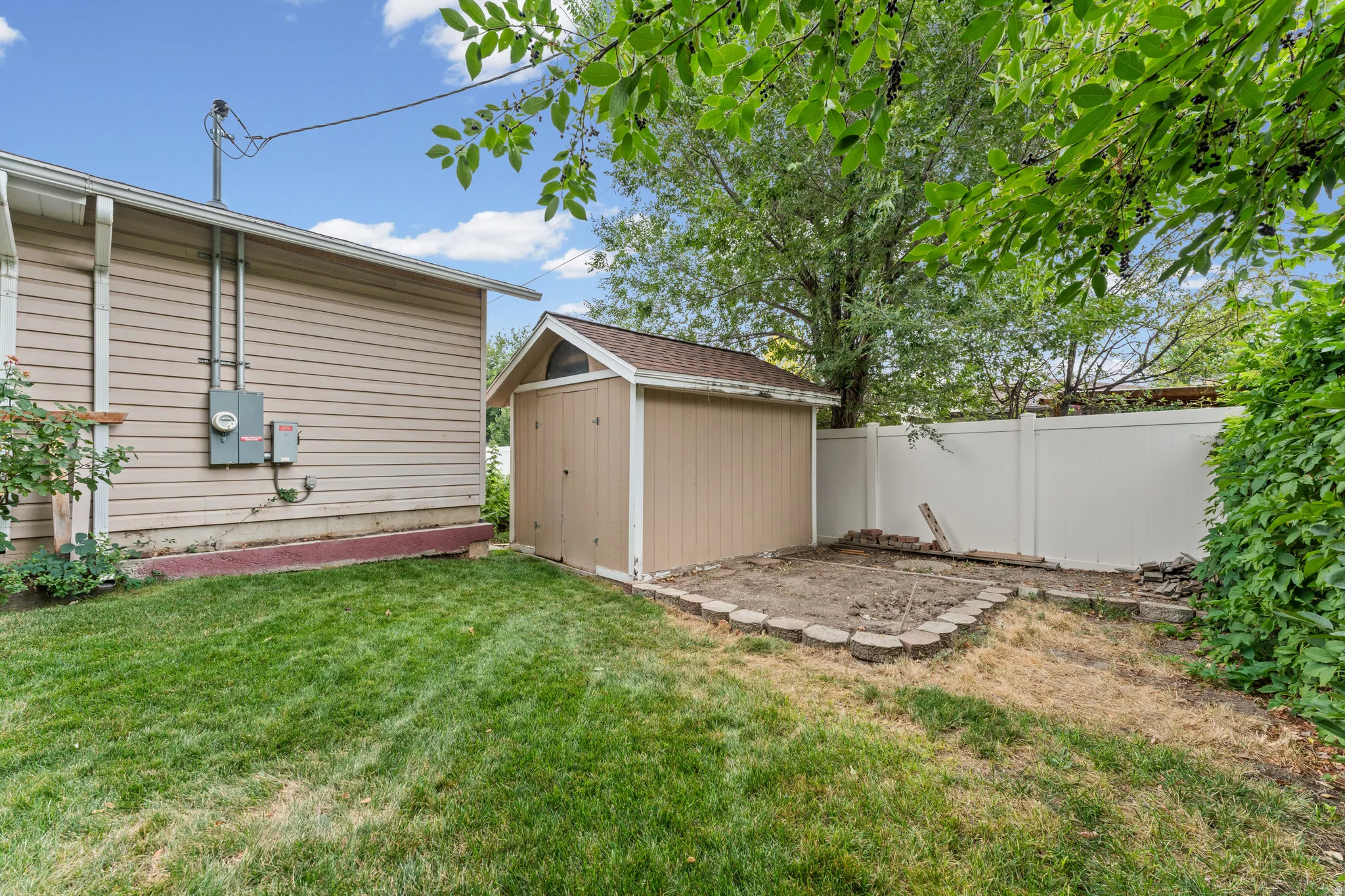Rear yard featuring a storage shed, a white privacy fence, and a grassy area