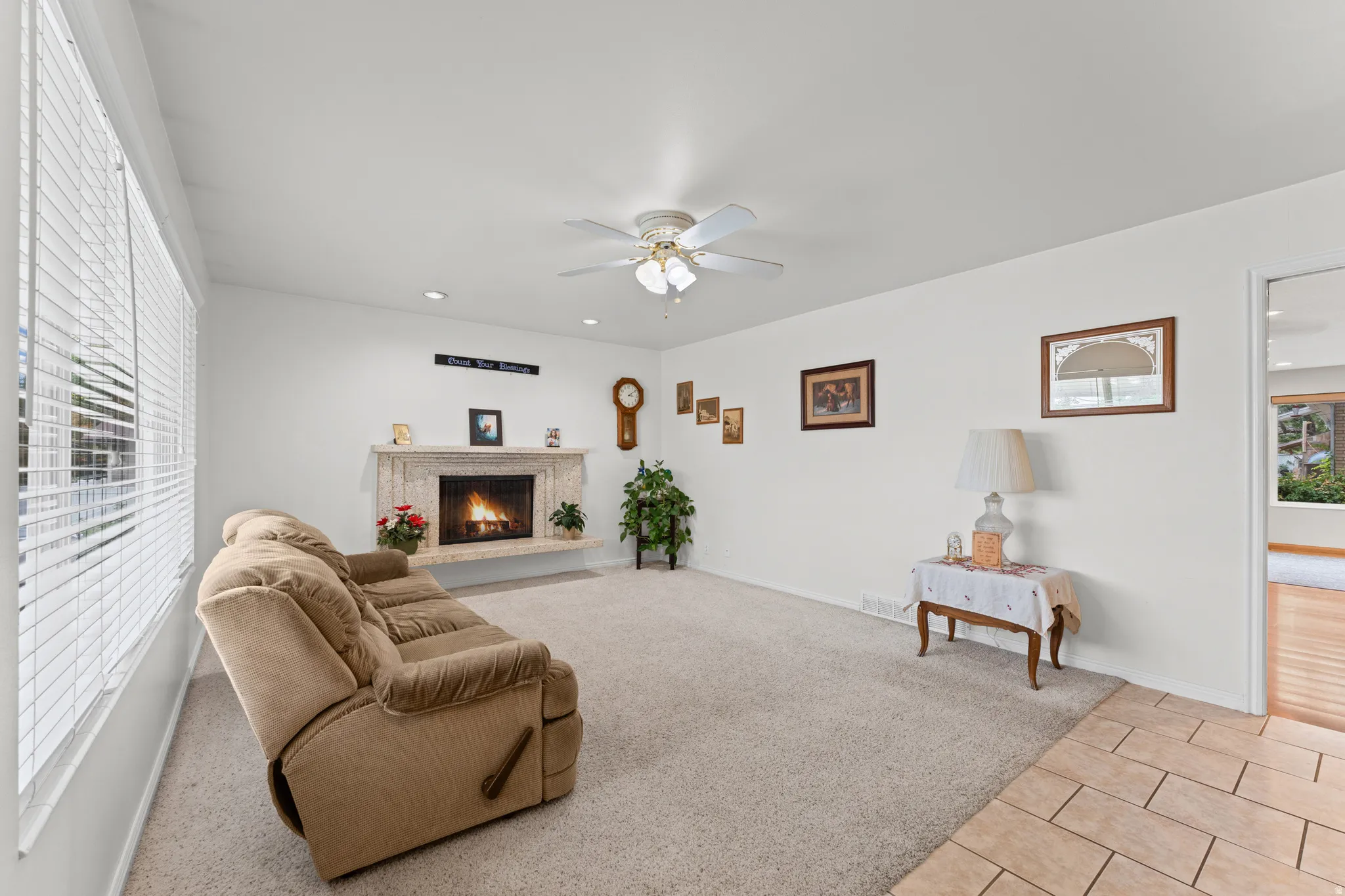 Living area featuring a stone-clad fireplace, ceiling fan, recessed lighting, and carpet flooring