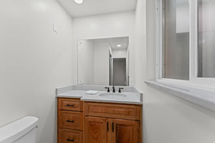 Wood-finish vanity with an integrated basin sink, light-toned countertop, and dark-toned hardware