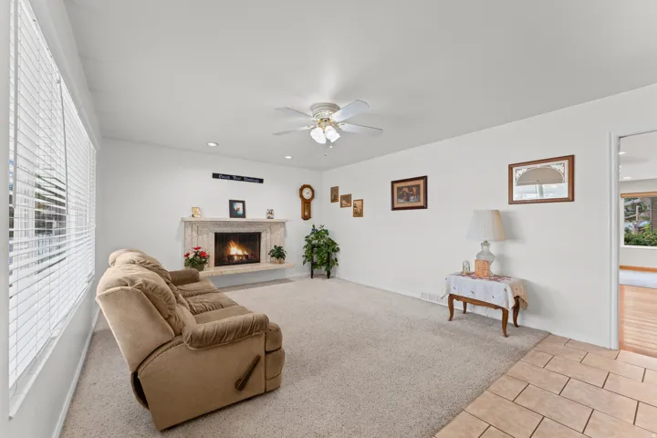 Living area featuring a stone-clad fireplace, ceiling fan, recessed lighting, and carpet flooring