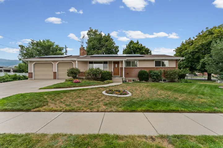 Ranch-style residence featuring a brick and siding exterior, an attached two-car garage, solar panels, and a concrete driveway