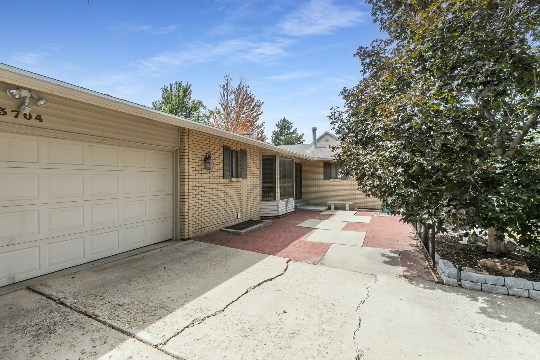 Single-story exterior featuring brick and siding, an attached garage, and an entryway with a screened enclosure