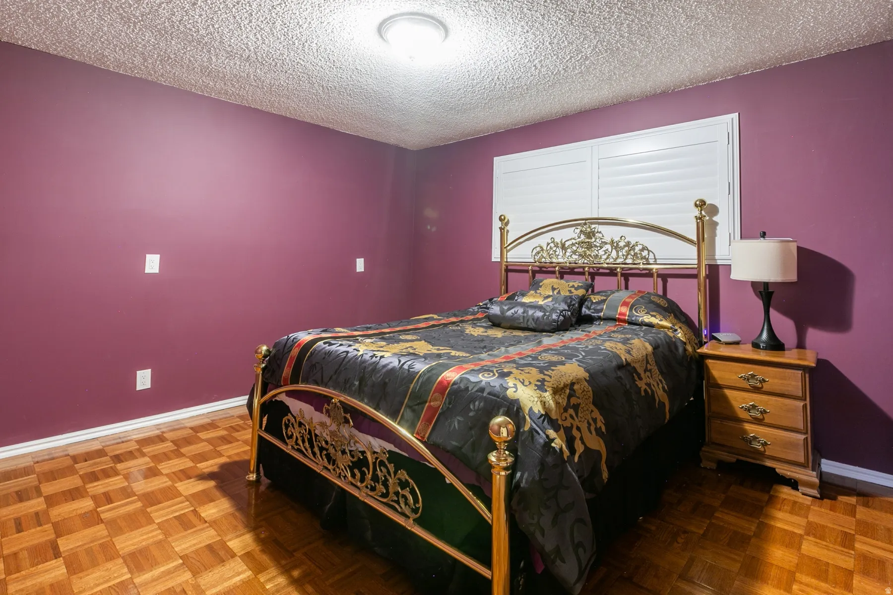 Parquet wood flooring, ceiling light fixture, window with white louvered shutters, and purple walls
