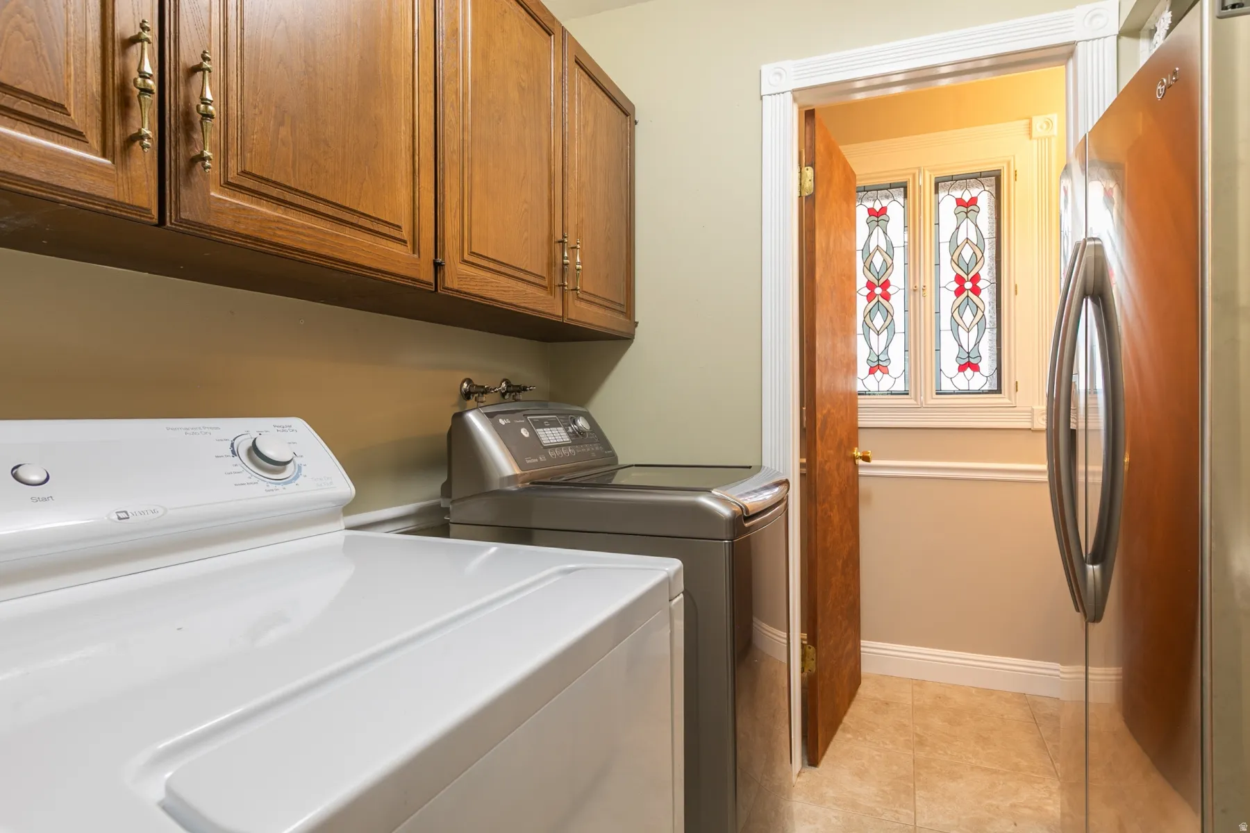Wood-finish cabinetry with brass hardware, tiled flooring, and decorative stained-glass windows