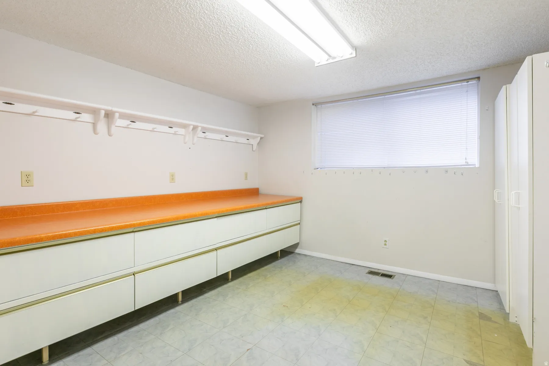 Built-in cabinetry with an orange countertop, overhead shelving, window with blinds, and recessed lighting
