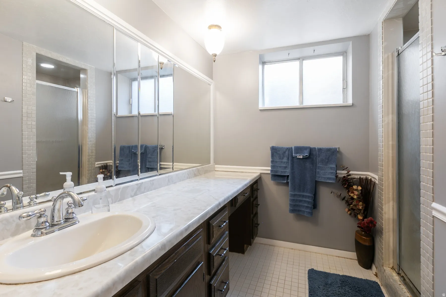 Vanity with integrated sink, chrome faucet, and expansive wall-mounted mirror