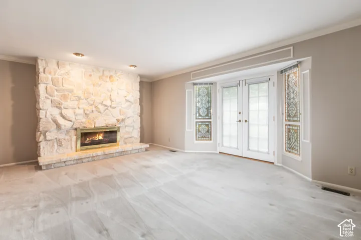 Stone-clad fireplace with a brass firebox, French doors with decorative glass panels, and recessed ceiling lighting