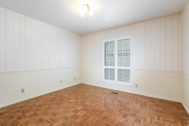 Parquet wood flooring, a window with horizontal blinds, decorative wall paneling, striped wallpaper, and a ceiling-mounted light fixture