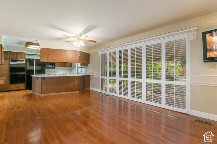 Hardwood flooring throughout, kitchen with built-in double ovens, breakfast bar, and ceiling fan